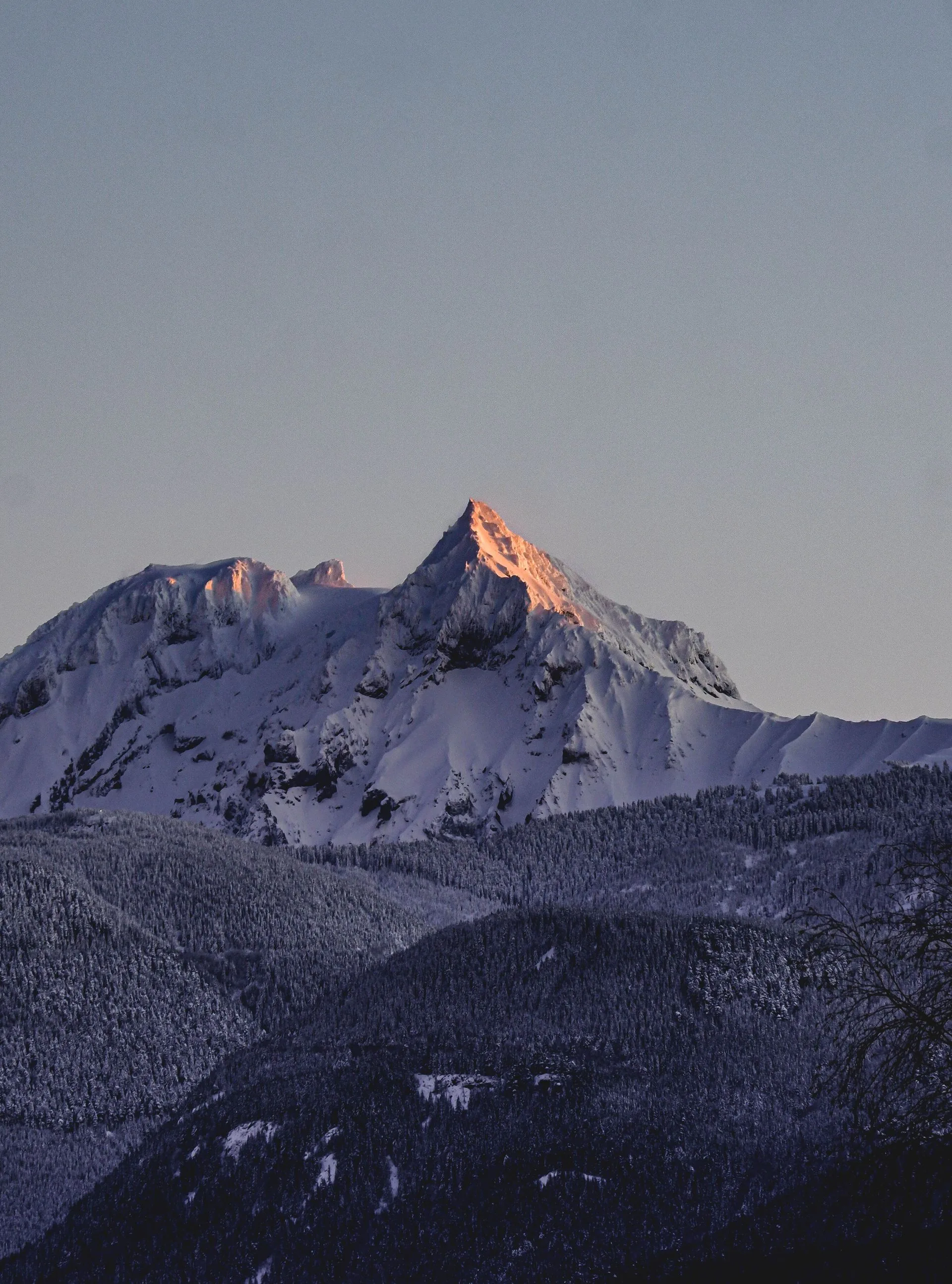 Captivating view of snow-covered mountain peak at sunrise with clear sky.